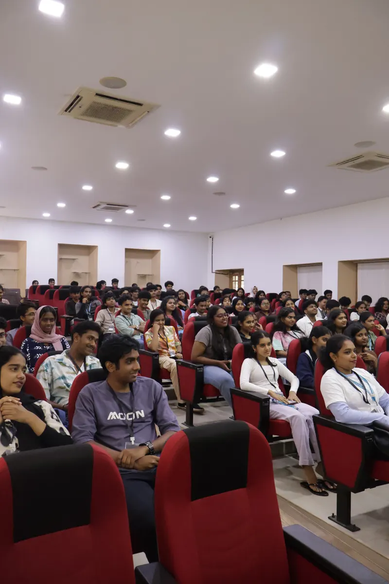 A wide view of the auditorium with most of the red seats filled