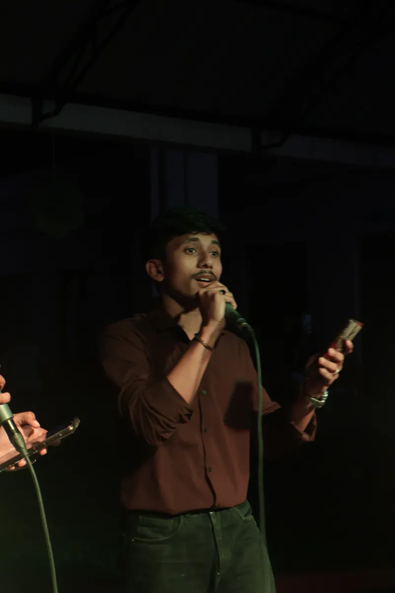 A student singing into a microphone under stage lights