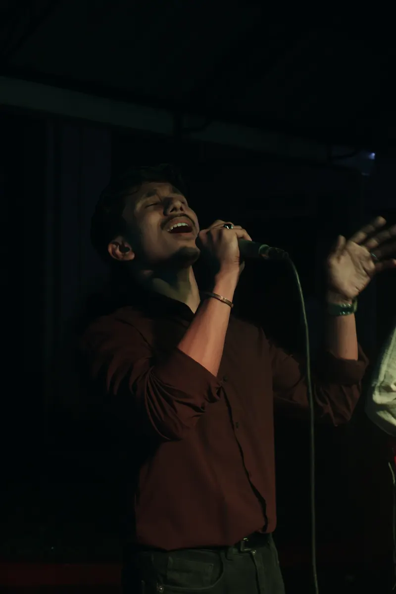 A singer mid-performance with arms outstretched