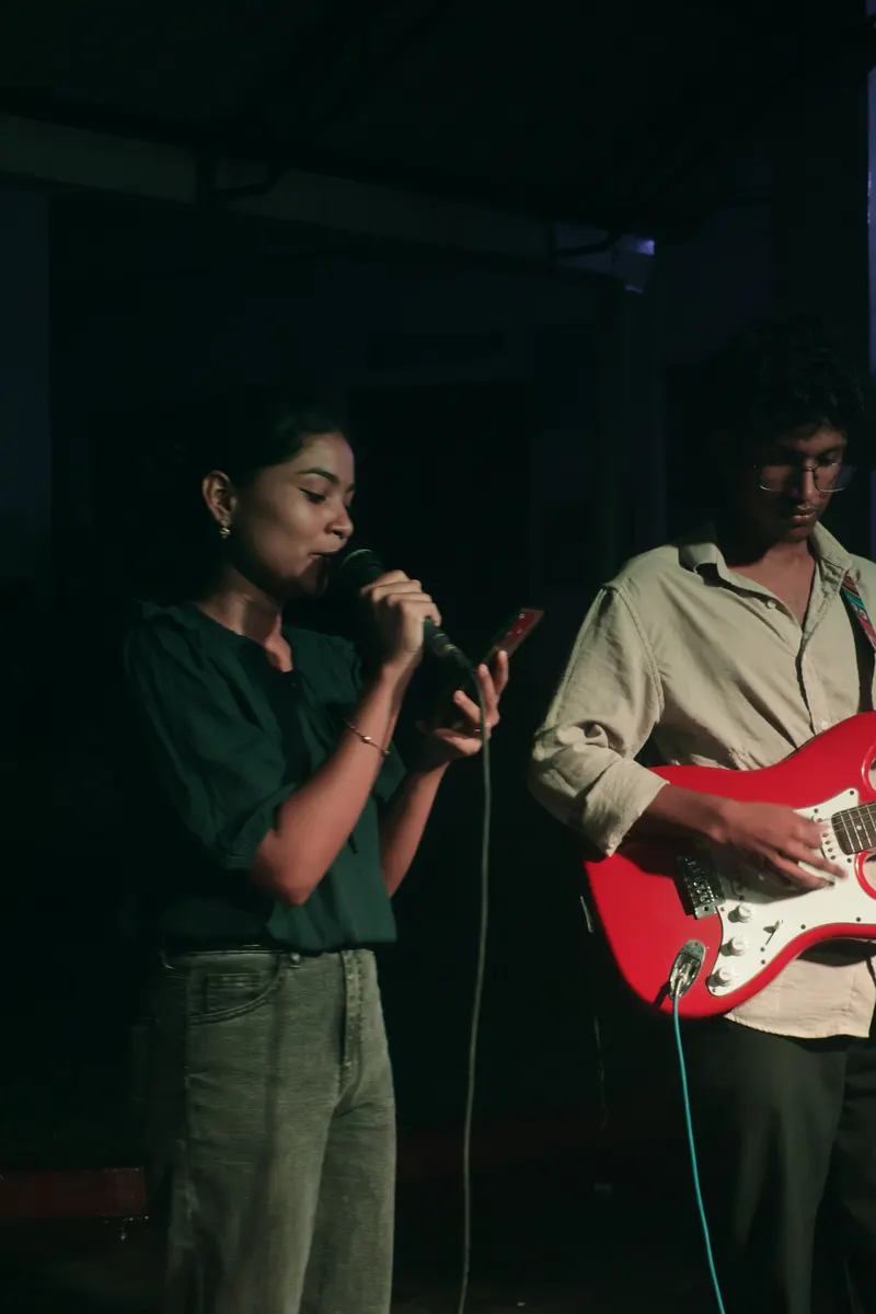 Two students performing together, one singing and one on electric guitar