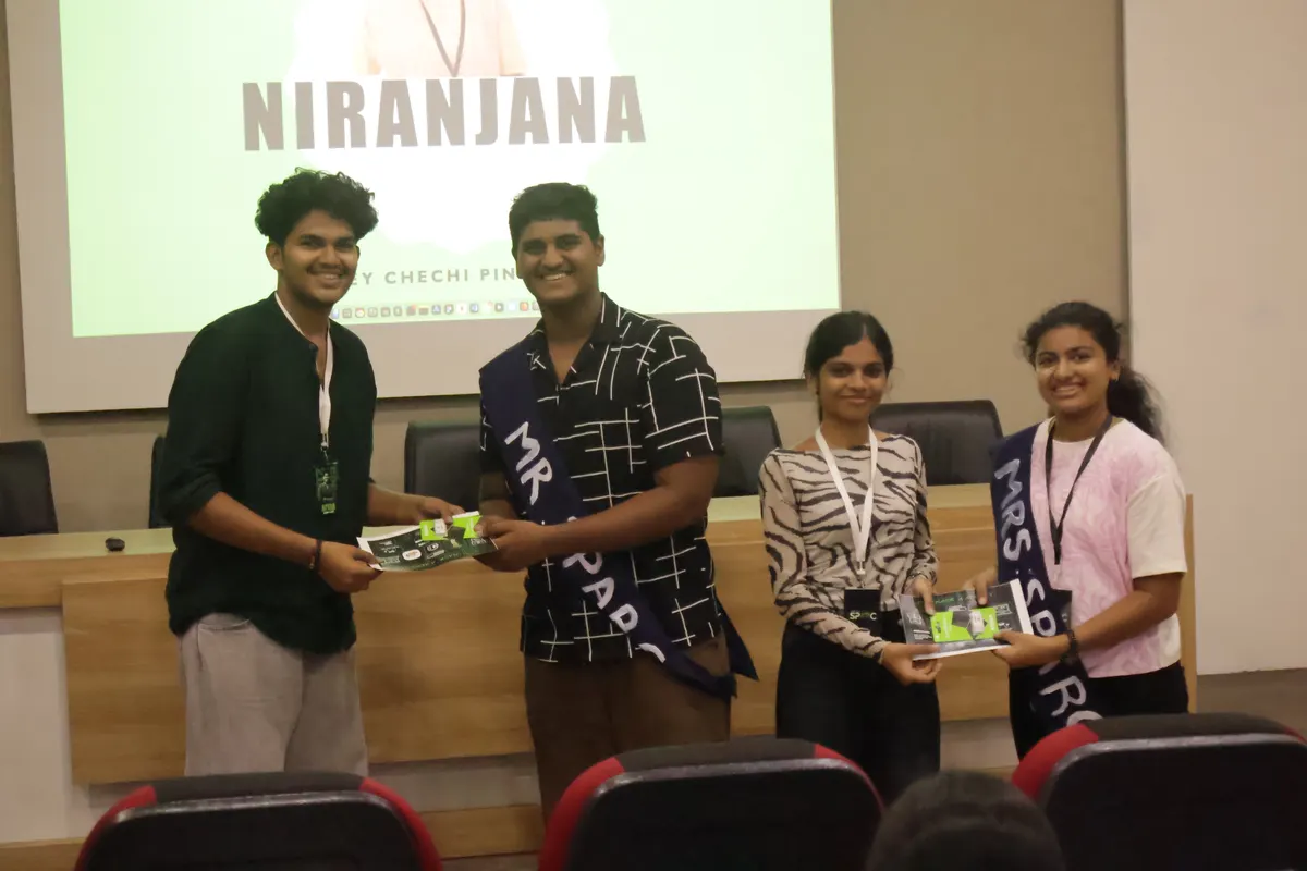 Students receiving a prize on stage in front of a presentation slide