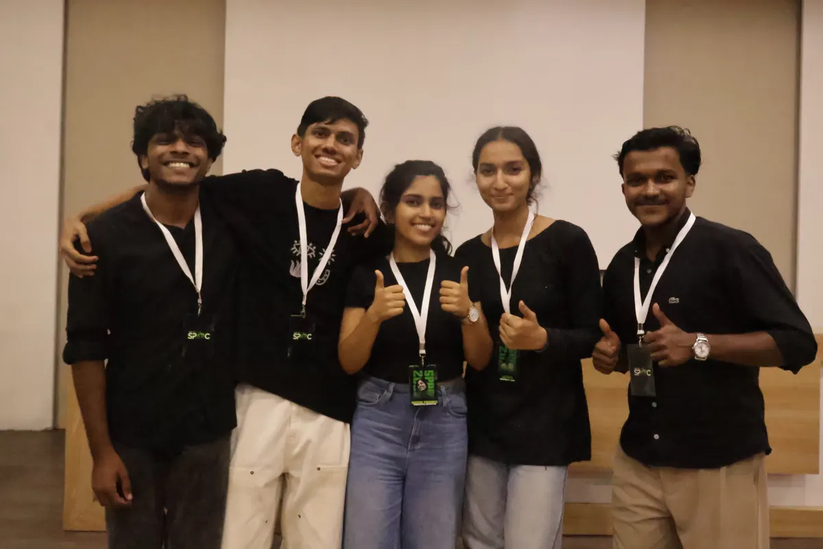 Five students posing arm in arm, event lanyards around their necks