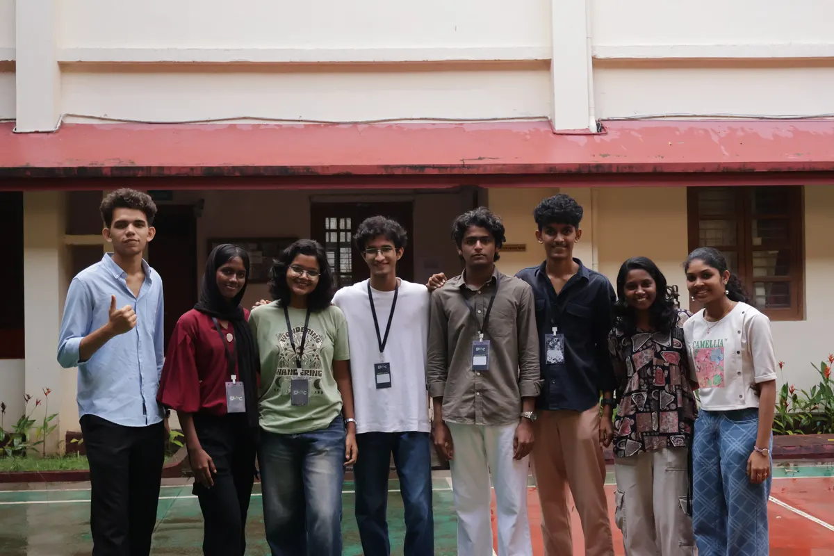 A group of students posing outdoors in front of the college building