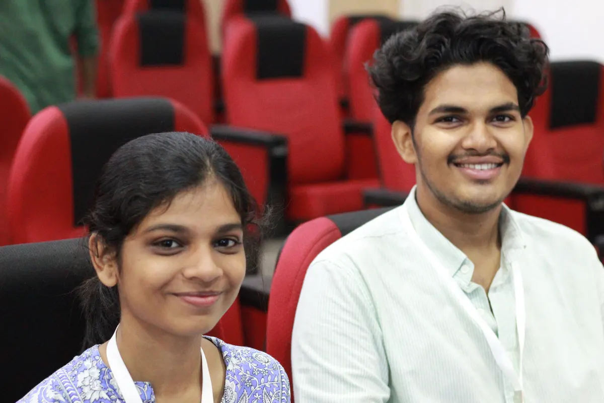 Two students smiling from their seats in the auditorium