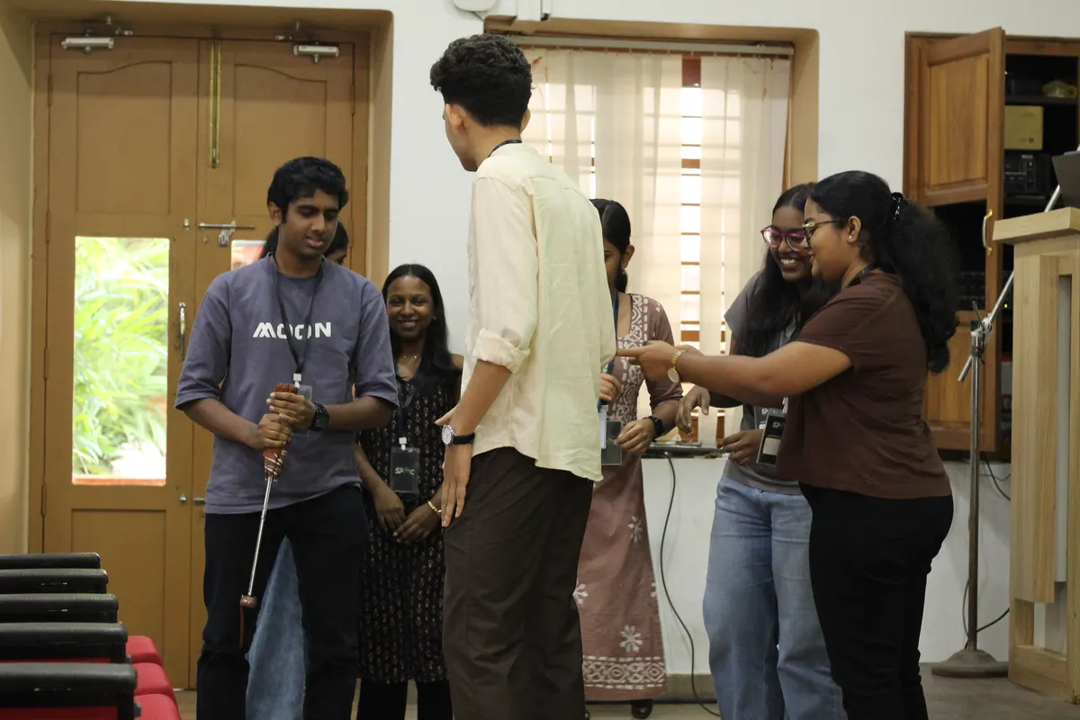 Students by the auditorium doorway, one handing something to another