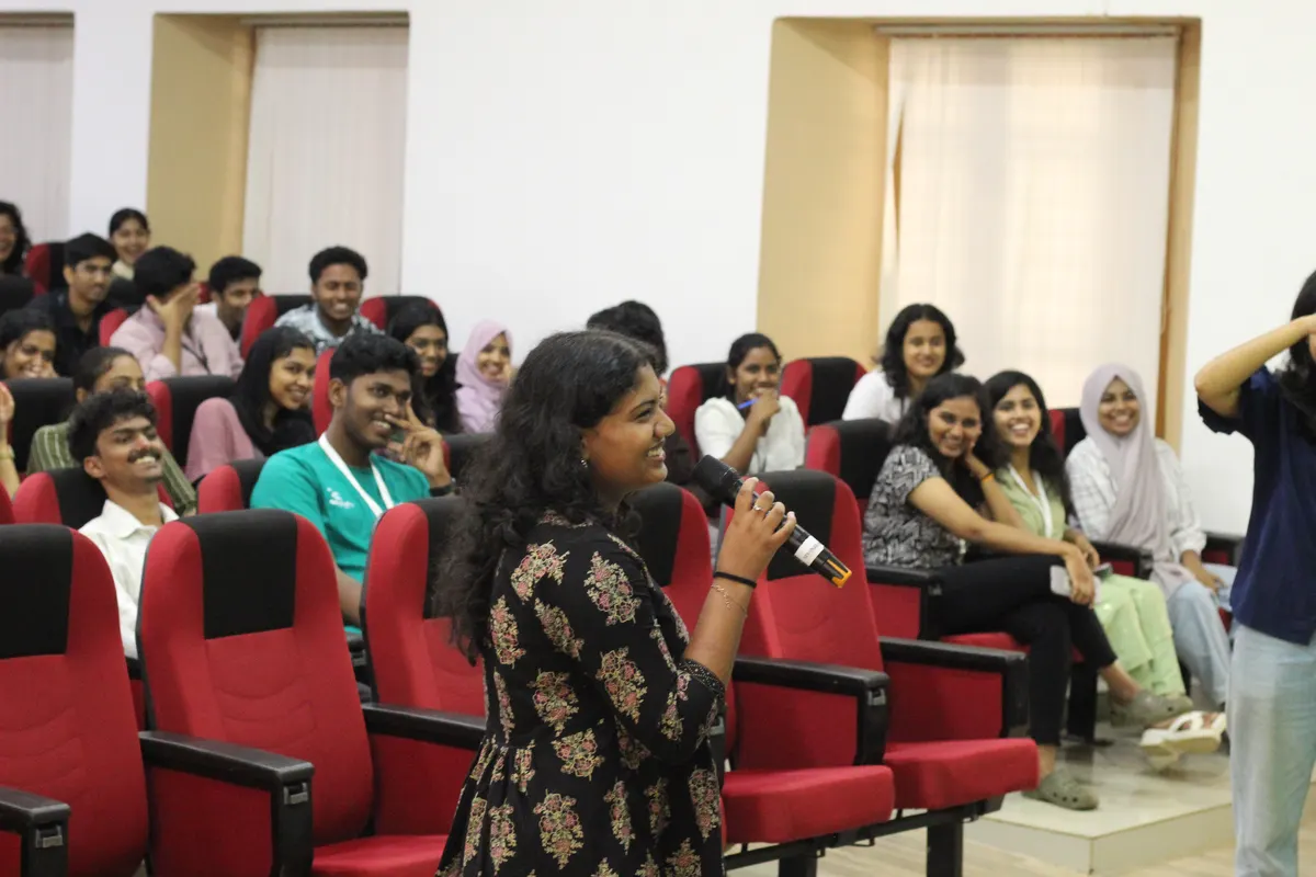 A student standing in the aisle of a full auditorium