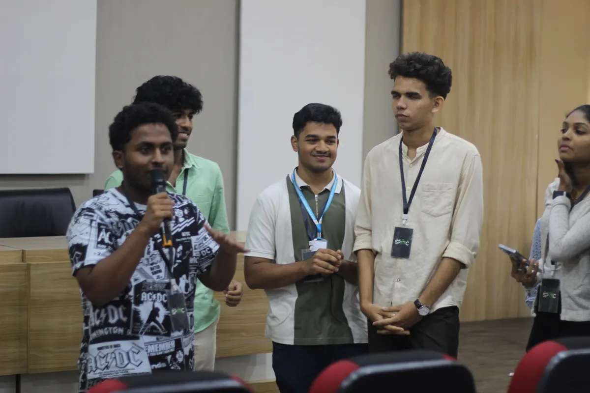 A student speaking into a microphone while others wait their turn