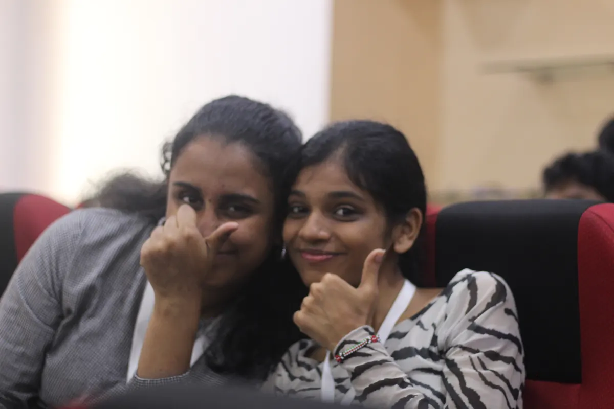 Two students smiling, one giving a thumbs up