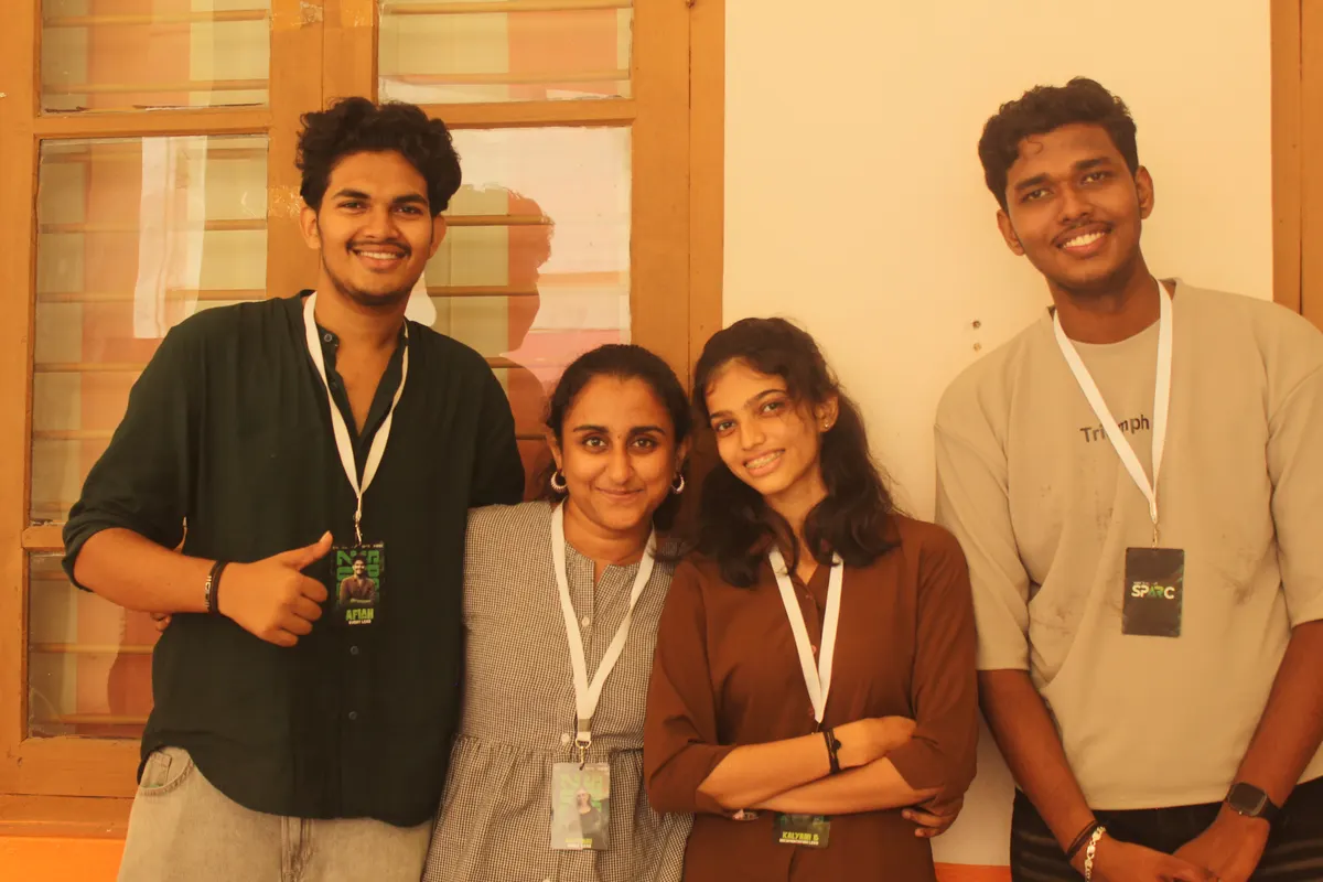 Four students posing together beside a window