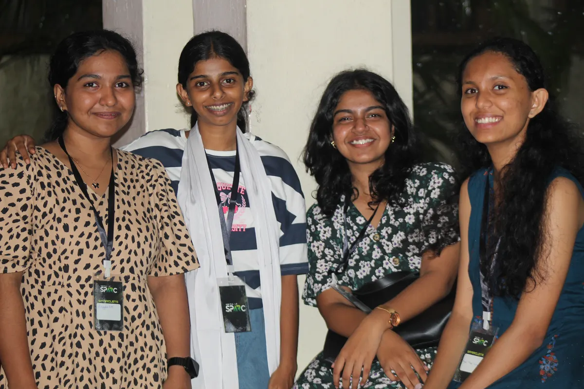 Four students posing together, arms around each other